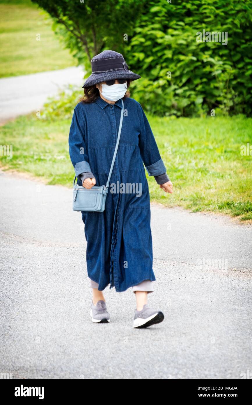 Une femme asiatique américaine marchant et portant son masque chirurgical lors d'un matin froid de printemps. Dans Little Bay Park, Whitestone, Queens, New York. Banque D'Images