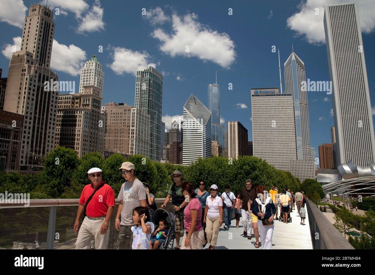 Vue latérale horizontale de près de certaines personnes traversant le pont de Renzo Piano Nichols, avec les gratte-ciel de Chicago comme arrière-plan, Millenium Park Banque D'Images