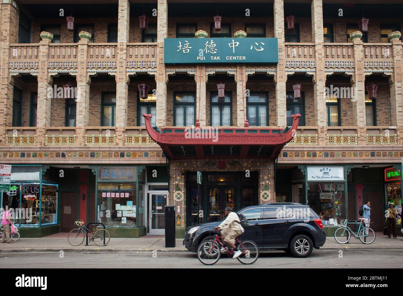 Vue horizontale d'un cycliste et d'une voiture passant par le centre communautaire Pui Tak, situé dans l'église chinoise historique, Chinatown, Chicago, Illinois, États-Unis Banque D'Images