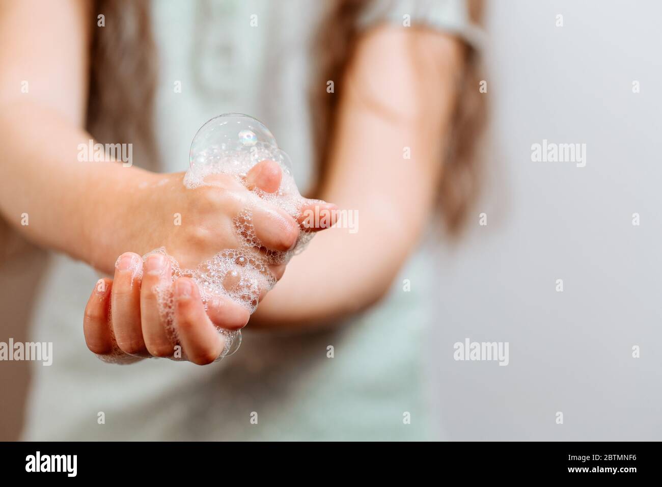 Mains d'enfants dans de la mousse savonneuse. Pandémie de coronavirus. Banque D'Images