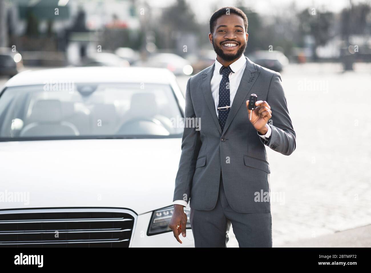 Un homme d'affaires africain heureux montrant la nouvelle clé automatique debout à l'extérieur Banque D'Images