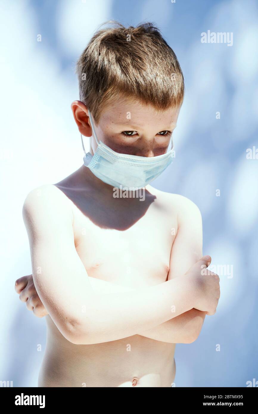Un garçon de 5 ans a photographié portant un masque facial PPE sur un fond blanc. Banque D'Images