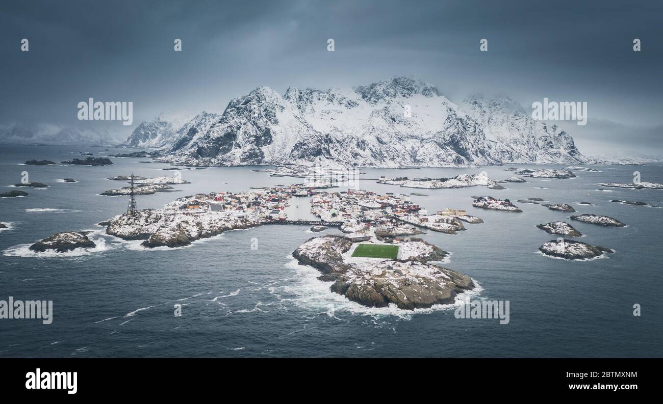 Superbe terrain de jeu de football situé à Henningsvaer, Lofoten, Norvège. Terrain de football vert sur une île rocheuse. Montagnes lointaines couvertes de neige. Antenne Banque D'Images