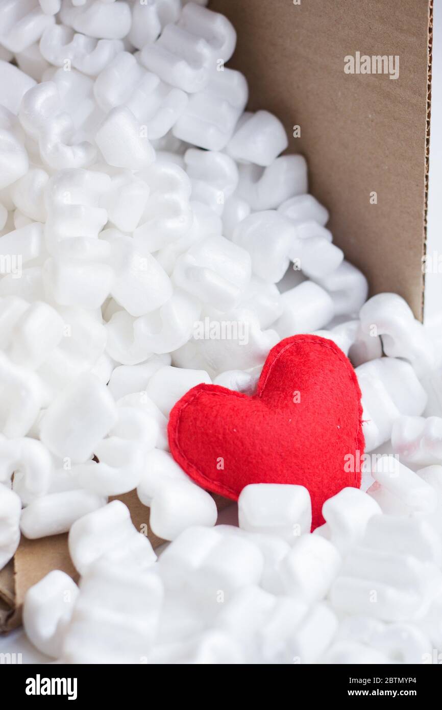Boîte d'emballage en feutre rouge à coeur remplie de nombreuses pastilles de styromousse blanches. Livraison avec amour Banque D'Images