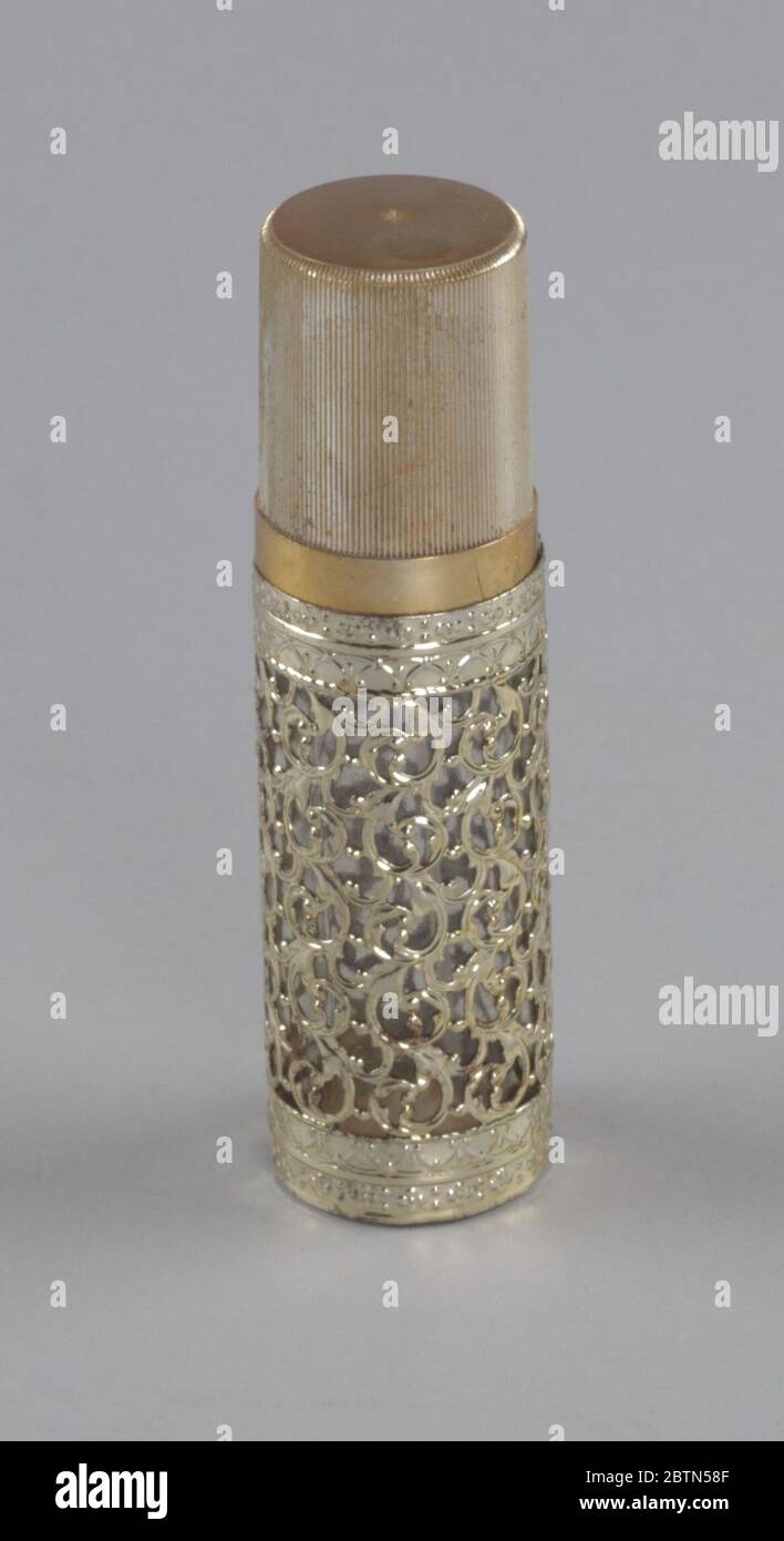 Bouteille de parfum en or et verre de la boutique de Millinery Maes. Une bouteille de parfum cylindrique (a) en verre transparent recouverte d'un design ajouré en métal doré. Le flacon est équipé d'un gicleur de pulvérisation à commande par pression. Une étiquette du fabricant sur le fond de la bouteille indique: 'Spray Parfum / Feminique / Renard Dist. Banque D'Images