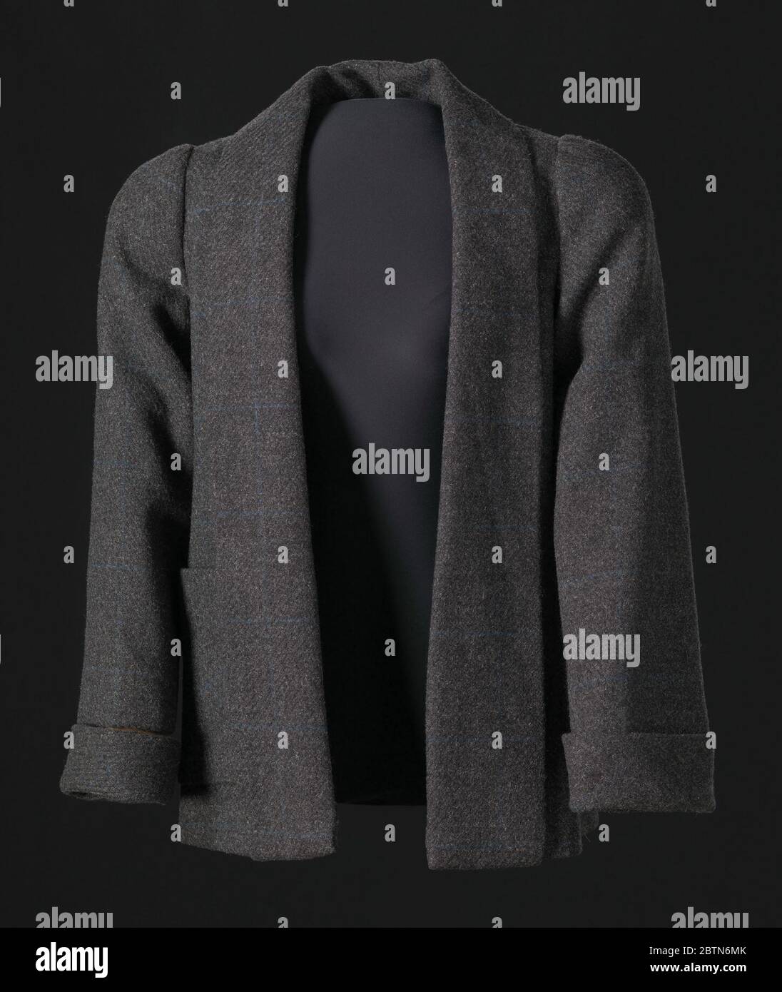 Veste grise conçue par Arthur McGee. Veste en tweed en laine grise conçue par Arthur McGee. La veste est dotée de manches longues droites ouvertes sur le devant avec poignets pliés et est coupée en trapèze tombant au niveau des hanches naturelles. Le col est replié et les revers sont droits et s'étendent sur toute la longueur de l'avant jusqu'à l'ourlet inférieur. Banque D'Images