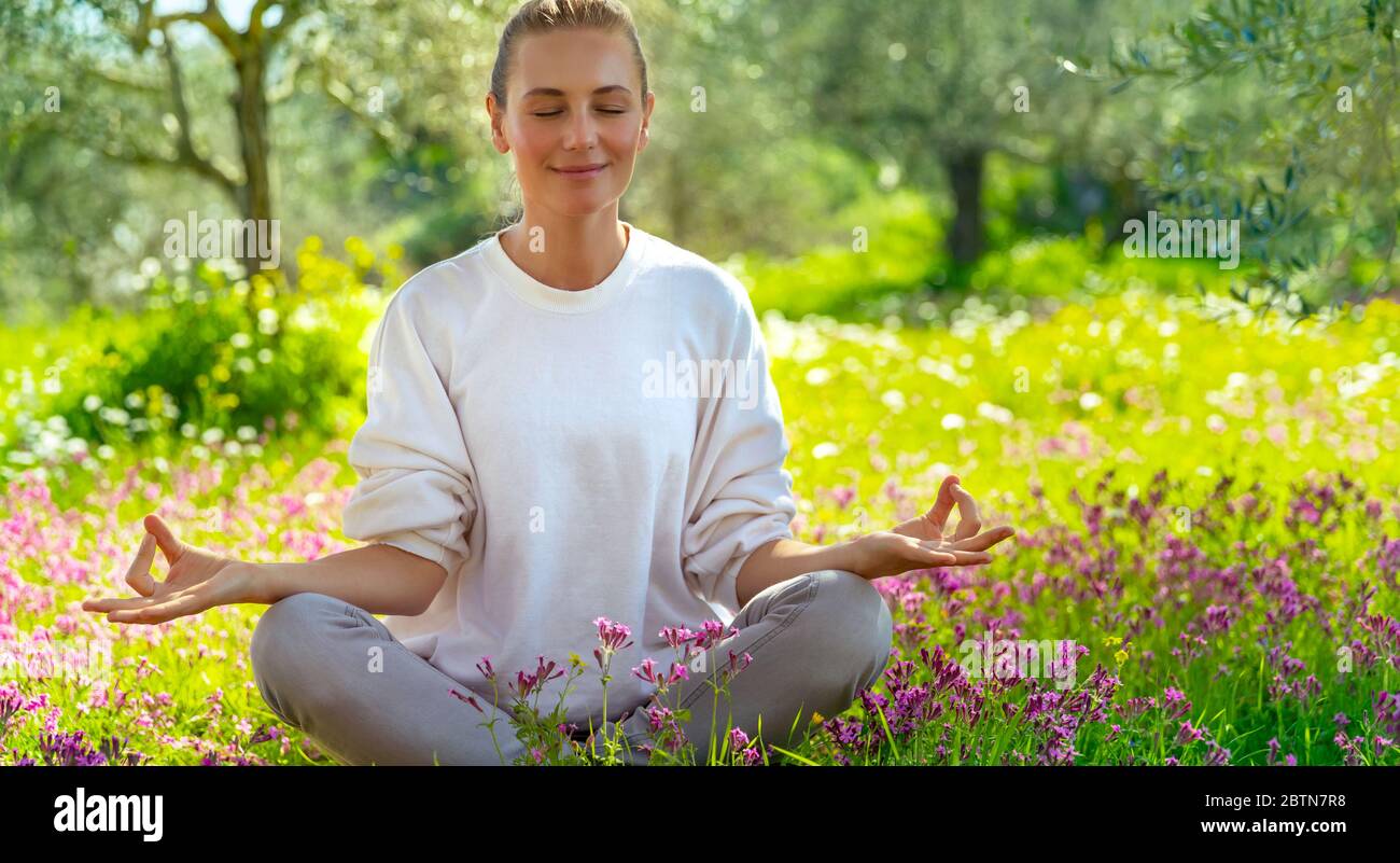 Belle fille calme avec les yeux fermés méditant dans le jardin frais en fleurs, l'unité avec la nature, l'équilibre zen, un mode de vie sain heureux Banque D'Images
