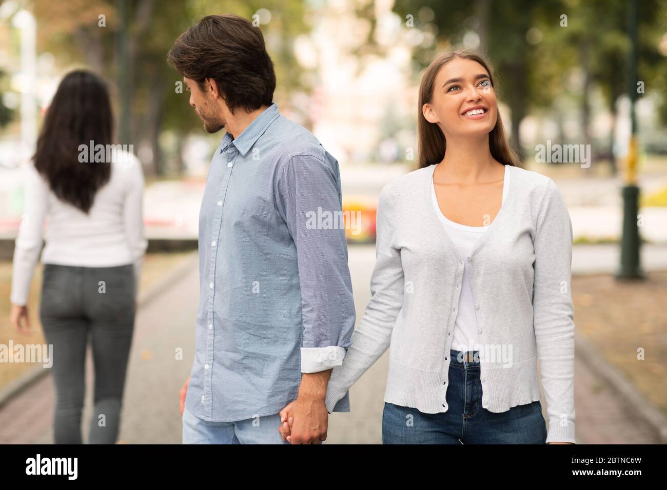 Petit ami regardant une autre femme marchant avec une petite amie à Park Banque D'Images