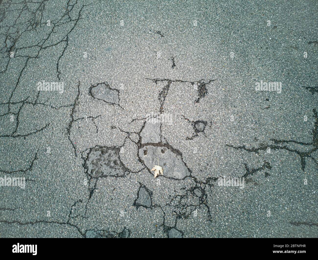 Ancienne route - surface d'asphalte gris fissuré - texture rapprochée Banque D'Images