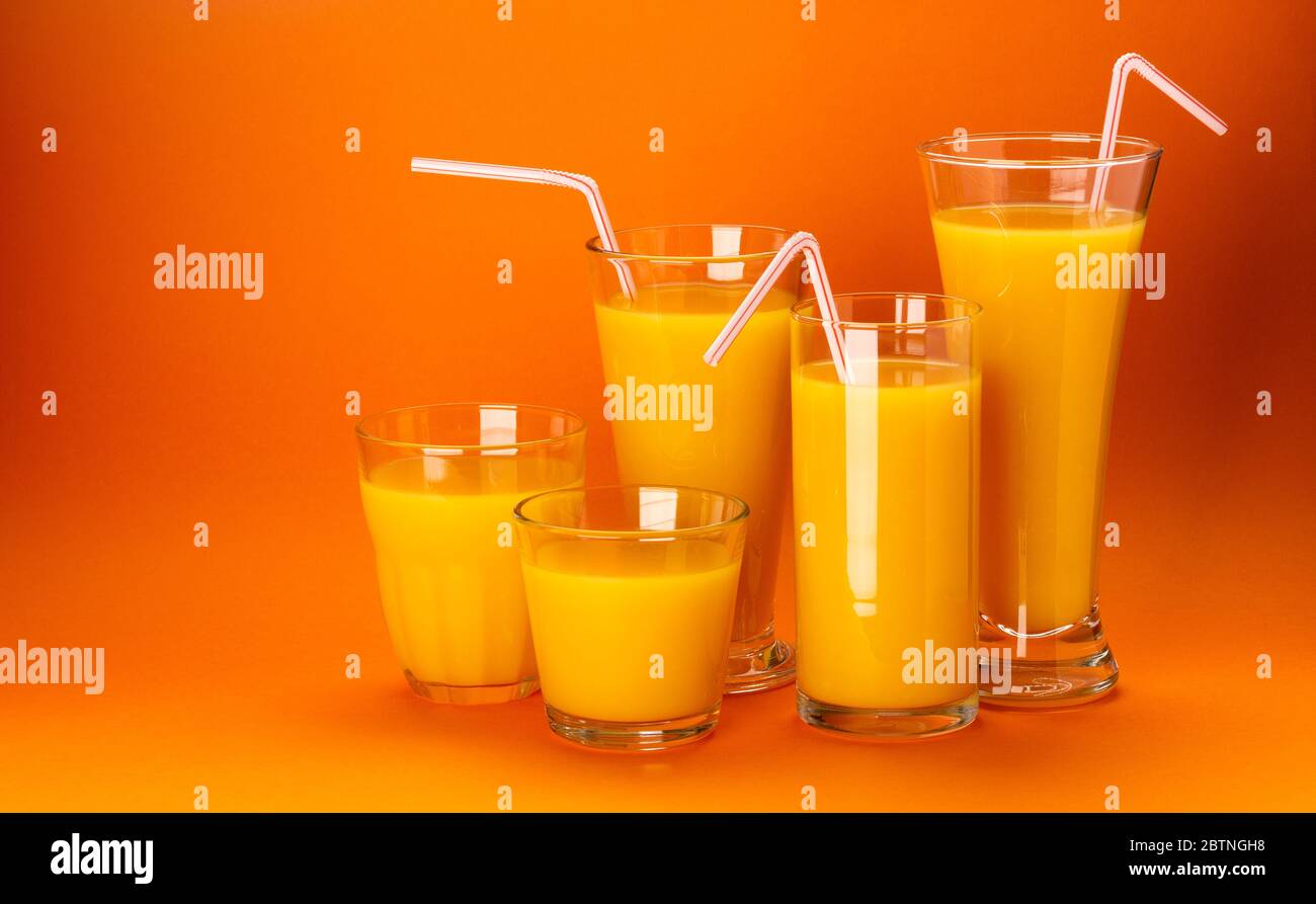 Verres de jus d'orange isolés sur fond orange de couleur Banque D'Images