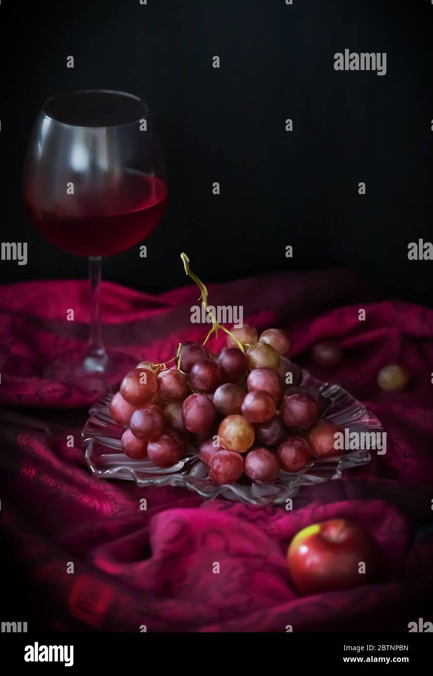 Une vie encore floue avec un verre de vin rouge, de raisins et de pommes sur un fond sombre avec un espace de copie Banque D'Images