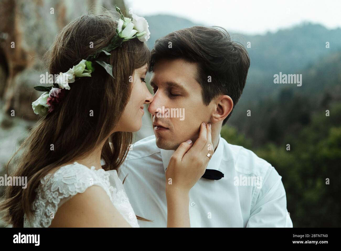 un couple de jeunes mariés de luxe se serpenchant avec tendre sur le sommet d'une montagne dans la soirée Banque D'Images