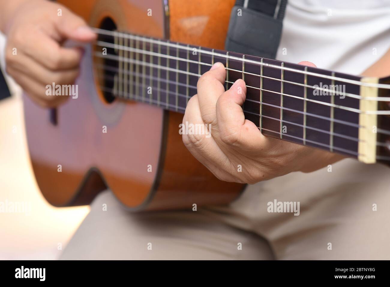 Mains du guitariste, jouant une mélodie sur une guitare acoustique en bois à six cordes Banque D'Images