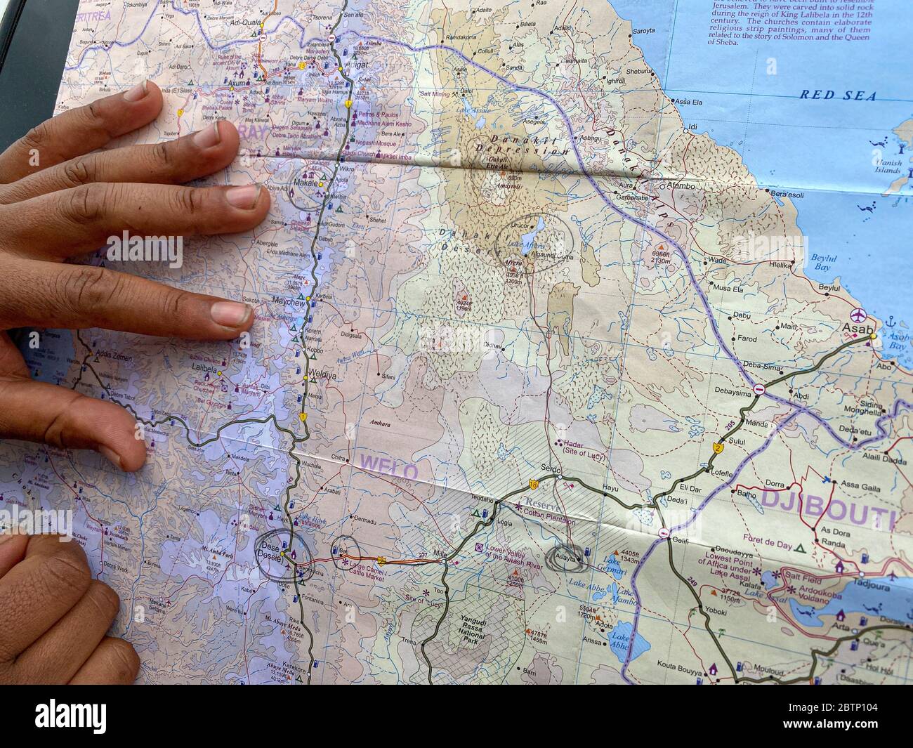 Mains de touristes avec carte pour la planification du voyage à la dépression de Danakil, région d'Afar, Ethiopie, Afrique Banque D'Images