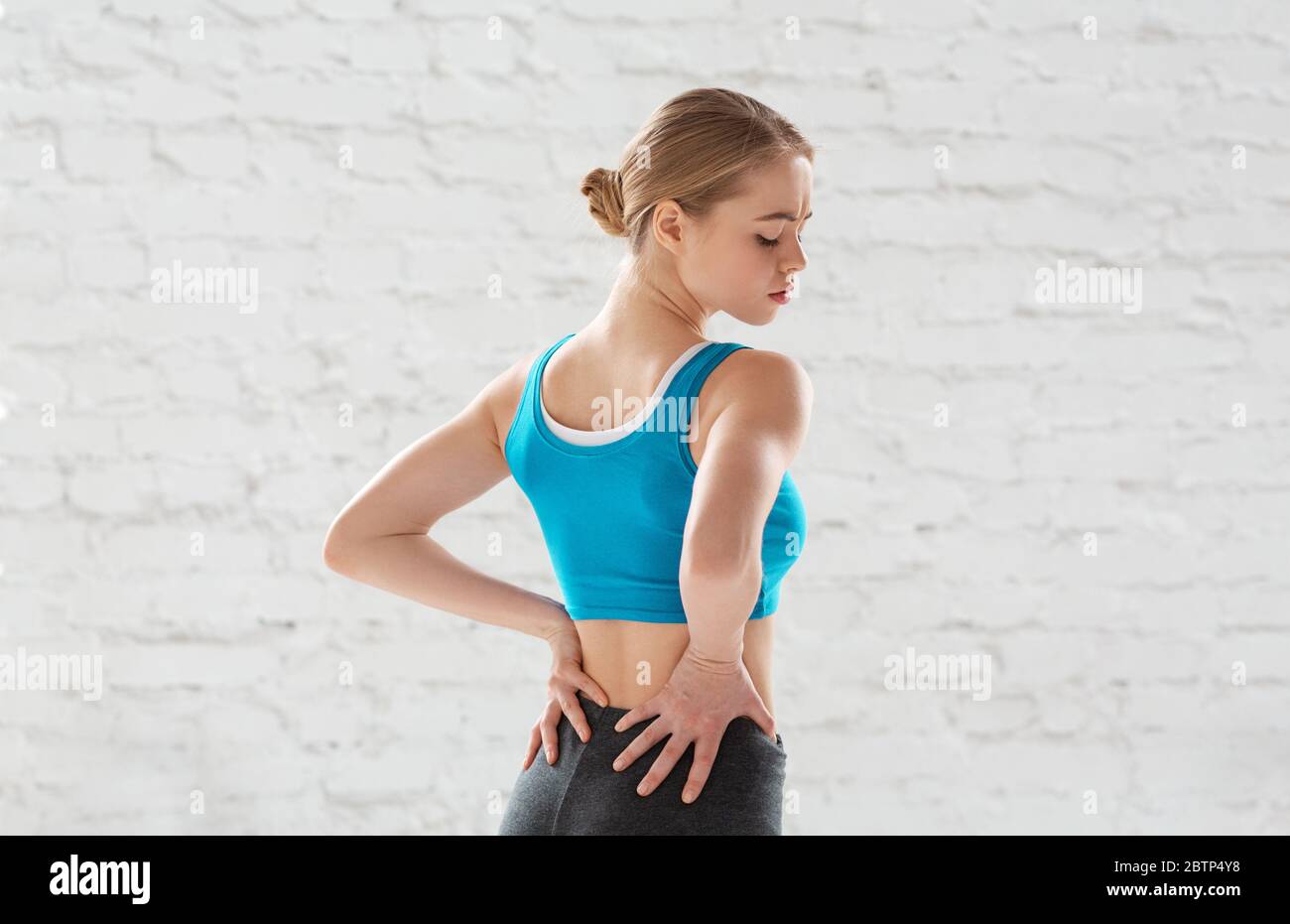Jeune femme attrayante souffrant de douleurs au dos liées au sport à la salle de gym Banque D'Images