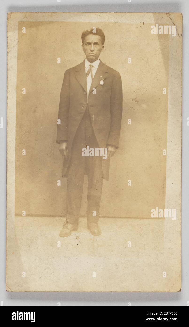 Carte postale photographique d'un homme en costume. Carte postale photographique d'un homme non identifié en costume. La photographie en longueur montre l'homme face à l'appareil photo avec ses mains sur le côté. Près de son épaule gauche est une médaille qui est accrochée à sa veste. Banque D'Images