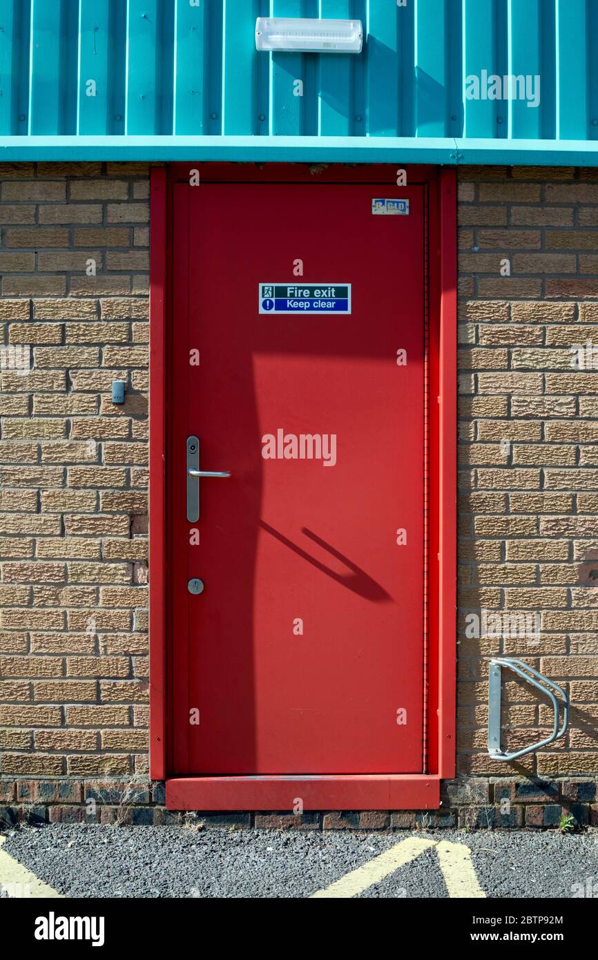 Une porte de sortie de secours rouge sur une petite usine, Warwick, Royaume-Uni Banque D'Images