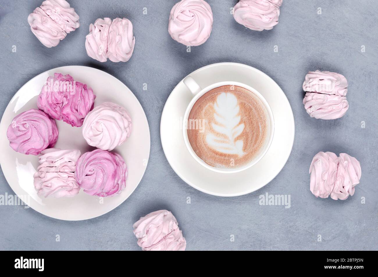 Café chaud avec art latte et marsmalow rose sur fond gris concept de Saint Valentin. Vue de dessus Banque D'Images
