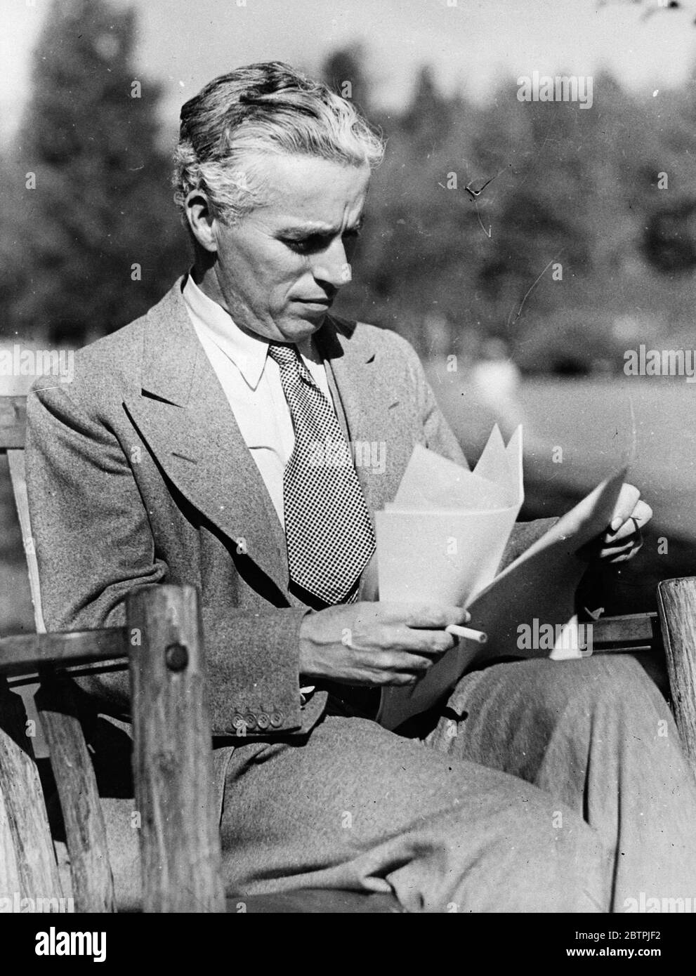 Un autre film de Chaplin bientôt . Charlie Chaplin est bientôt à produire et apparaître dans un nouveau film . L'histoire a reçu son attention au lac Arrowhead , Californie , où il est en vacances . La photo montre Charlie Chaplin lisant l'histoire de son nouveau film à Lake Arrowhead . 14 septembre 1934 Banque D'Images
