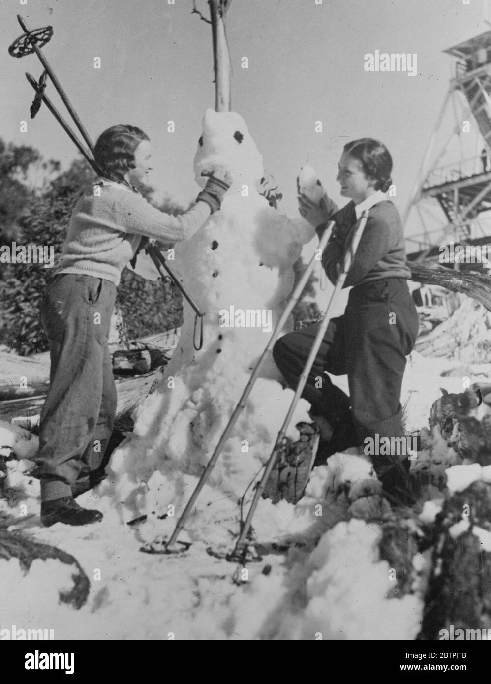 Lorsque trois sont entreprise . Les filles australiennes de sports d'hiver ont mis la touche finale à un bonhomme de neige dans les montagnes près de Melbourne . 2 novembre 1935 Banque D'Images