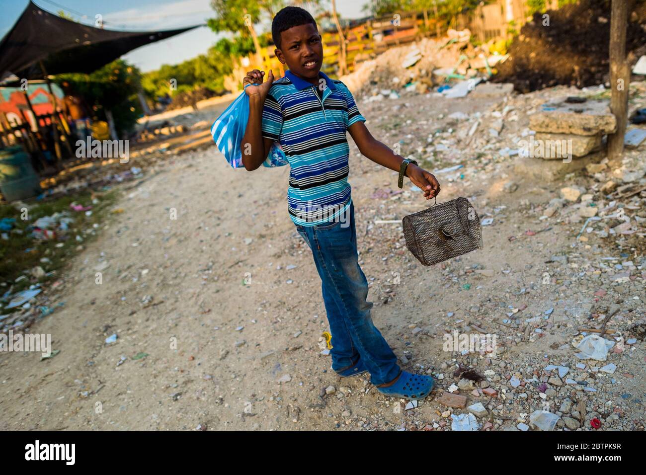 Un garçon colombien porte une petite cage à oiseaux, avec un canari sauvage à l'intérieur, dans le quartier Olaya Herrera à Cartagena, en Colombie. Banque D'Images