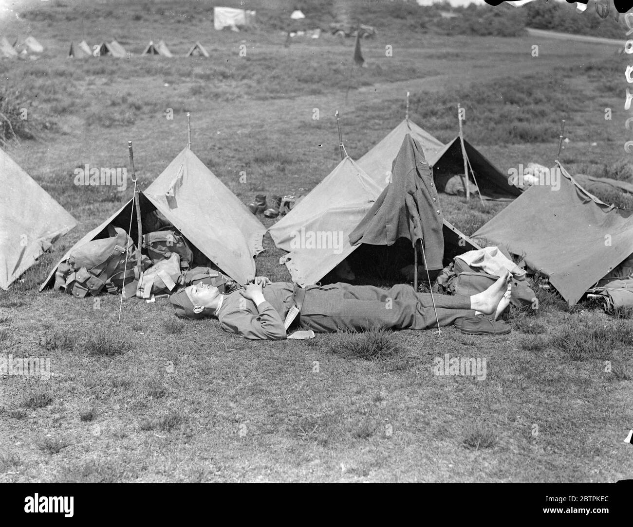 Repos sur le mars . Troupes d'Aldershot sur les manoeuvres . Marche de Aldershot en début de matinée , les troupes de la 2e Division , Marlborough Lines , défilent dans Sussex lors de leurs manœuvres annuelles . Ils effectuent des actions imitaux le mars . Photos : UN soldat se réinvente de ses lourdes bottes en se reposant sur Frensham Common , Aldershot après le jour ' s mars . 27 juillet 1936 Banque D'Images