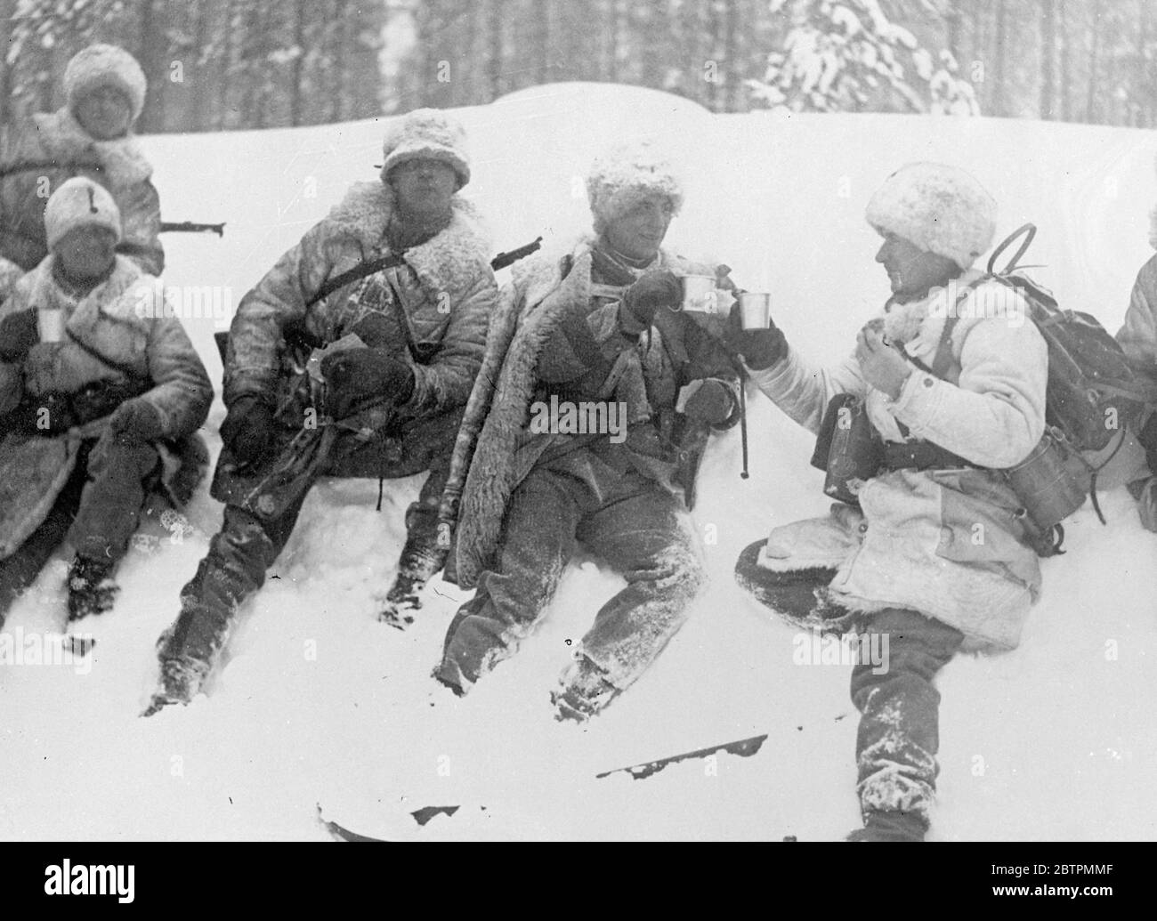 Soldats en fourrures . Armée suédoise sur des manœuvres dans les déchets de neige de laponie . L'armée suédoise est en train d'être testée de manière sévère dans des conditions hivernales difficiles dans le district de Boden en laponie . Les exercices sont suivis par le Prince héritier , Gustav Adolf . Toutes les forces d'infanterie sont équipées de skis et la plupart de l'artillerie de traîneaux . Les fourrures sont l'uniforme prédominant . Photos , soldats suédois en fourrure prenant des boissons chaudes comme ils se reposent dans la neige du champ de bataille à Boden , Laponie . 11 mars 1937 Banque D'Images