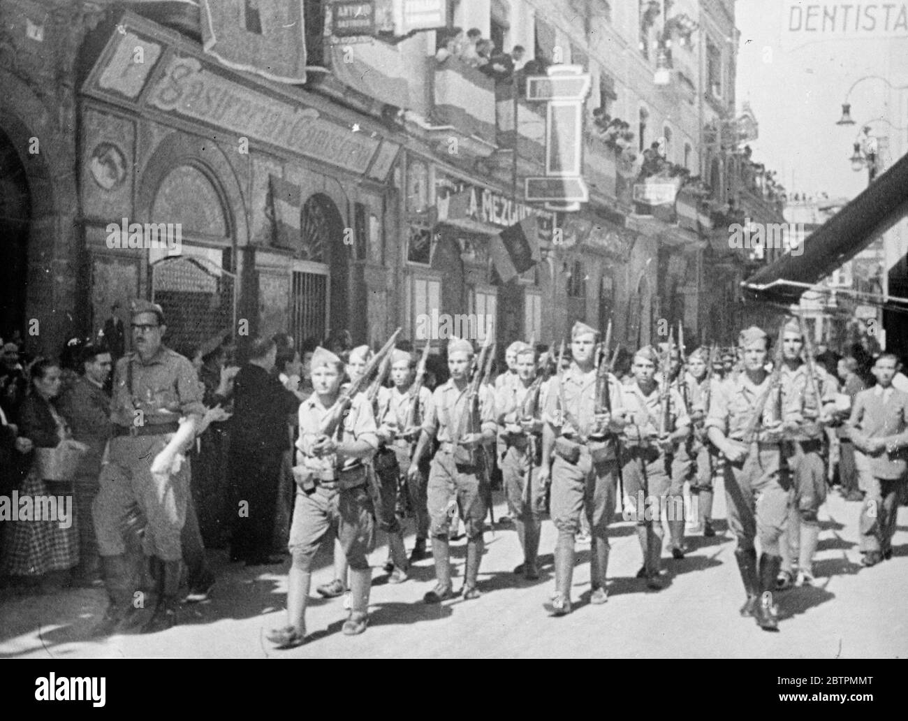 Les troupes rebelles entrent dans Huelva . Avec la quasi-totalité de la population civile qui borde les rues , les troupes rebelles ont marché dans Huelva , la ville sur le front de Rio Tinto , qui a été capturée par les insurgés des loyalistes . Après que les rebelles aient pris possession de la ville , il y a eu des processions par des mouvements de jeunesse nationalistes et un examen des gardes civils . Photos : une colonne de troupes rebelles marchant dans Huelva . 11 septembre 1936 Banque D'Images