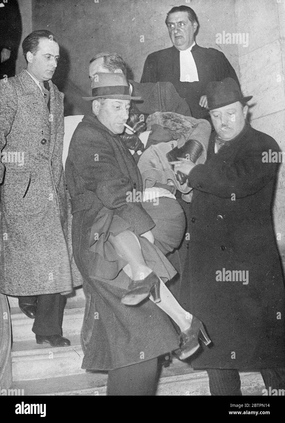 Mme Schmeder s'effondre au procès. Madame Irene Schmeder, accusée d'avoir tenté de tuer son amant dans une erreur en ligne, clame lorsqu'elle a comparu au Palais de Justice pour procès. La victime de la fusillade était le pilote français Pierre Lallamand . Ensuite, Mme Schmeder s'enfuit en Angleterre. Photos, Madame Irene Schmeder dans un état d'effondrement au Palais de justice. Son frère a le bras autour de ses épaules et en arrière-plan est l'avocat de Mme Schmeder , Maitre Thaon. 20 avril 1937 Banque D'Images