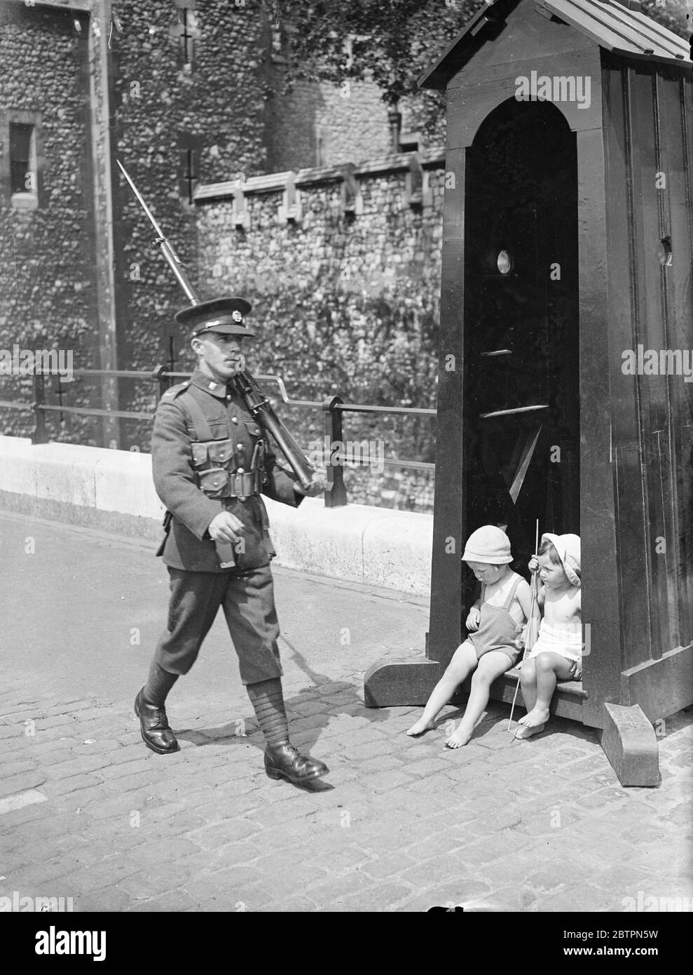 Changer de lieu ! Deux petits Londoniens se réfugient à l'ombre de la boîte de sentry à la tour de Londres a été le malheureux sentry est laissé à la merci du soleil!. 29 mai 1937 Banque D'Images