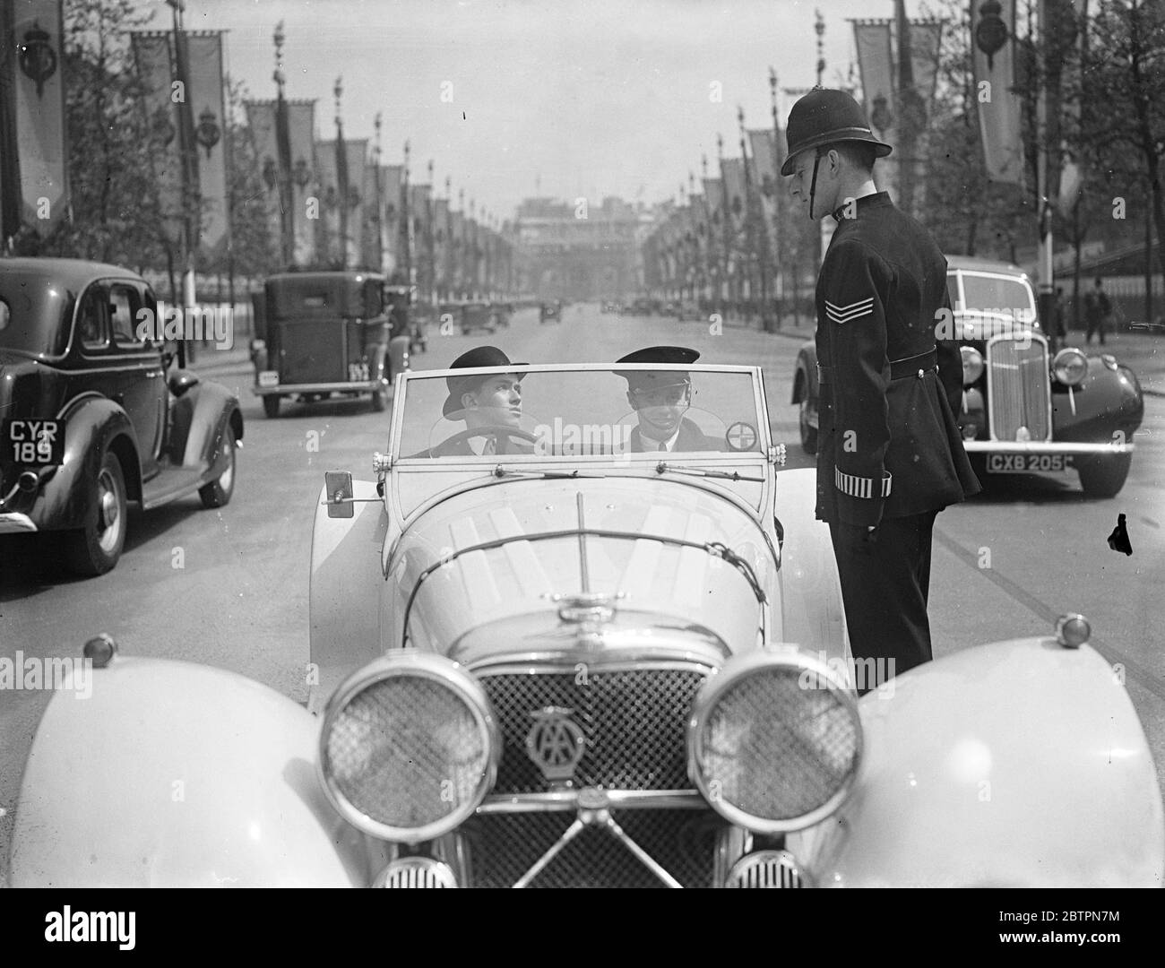 La loi donne un avertissement. La police adopte une nouvelle politique pour traiter les automobilistes qui se sentent enclins à la vitesse lorsqu'ils sont confrontés à la ligne droite du Mall. Ils sont arrêtés par des officiers en uniforme, avertis et autorisés à se rendre. Expositions de photos, le gendarme en uniforme qui arrête un automobiliste dans le Mall. 21 mai 1937 Banque D'Images