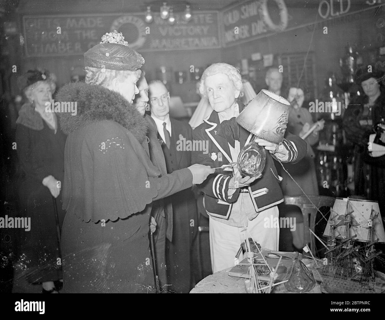 La Reine et la Reine Mary, parlent avec le vieux Crossman à la FIF Olympia. La Reine et la Reine Mary ont de nouveau visité la section Olympia de la British Industries Fair et ont manifesté un grand intérêt pour les expositions. Expositions de photos, la reine Mary, examinant un abat-jour montré par M. F A Saunders au stand de Messrs, S J Lethbridge. 24 février 1938 Banque D'Images