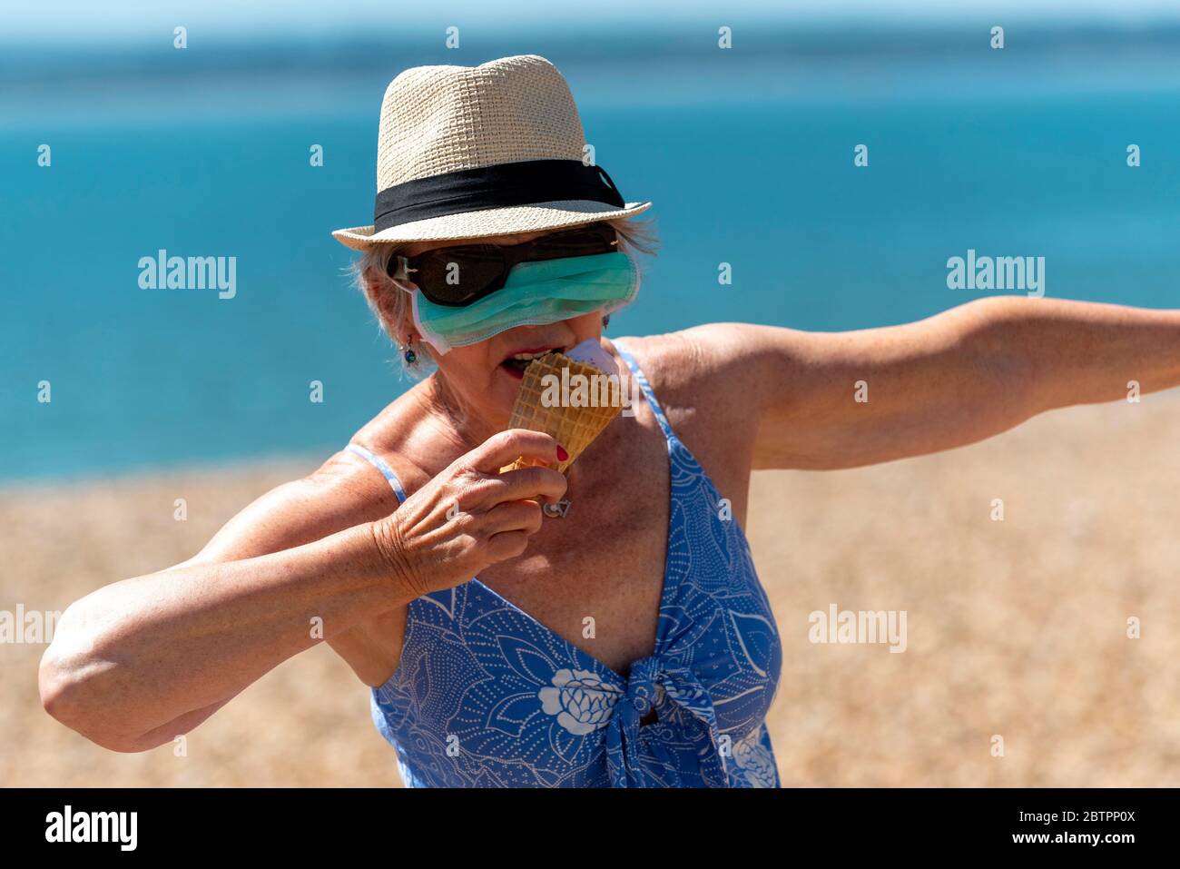 Southsea, Portsmouth, Angleterre du Sud, Royaume-Uni. Mai 2020. Femme mangeant de la crème glacée tout en portant un masque pendant l'épidémie de Corvid-19. Banque D'Images