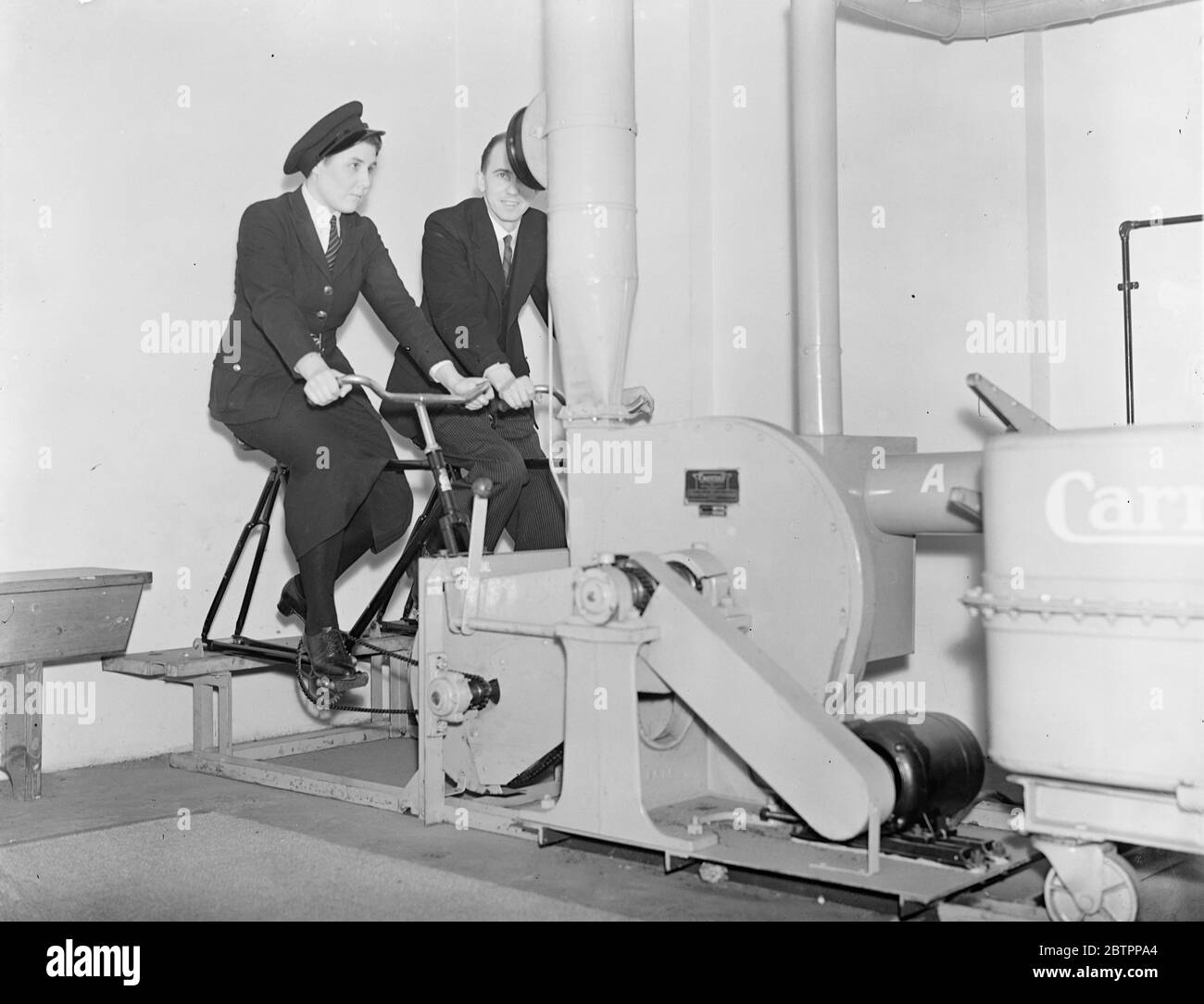 En pédalant le gaz toxique. Abri anti-RAID aérien à la banque de la ville. Un abri gaz entièrement équipé pour l'utilisation du personnel en cas de tarifs a été construit dans le sous-sol de la banque Yorkshire Penny à Cheapside. L'une des caractéristiques de l'abri est l'installation de filtration de l'air, qui est actionnée par deux personnes travaillant les pédales de cycle. L'air pollué de l'extérieur est purifié avant d'être admis dans la chambre. Les occupants pourraient faire fonctionner l'appareil à tour de rôle. En outre, il y a de nombreux magasins de nourriture et d'eau. Photos montre, un homme et une fille qui pédlent l'usine de filtration de l'air Banque D'Images