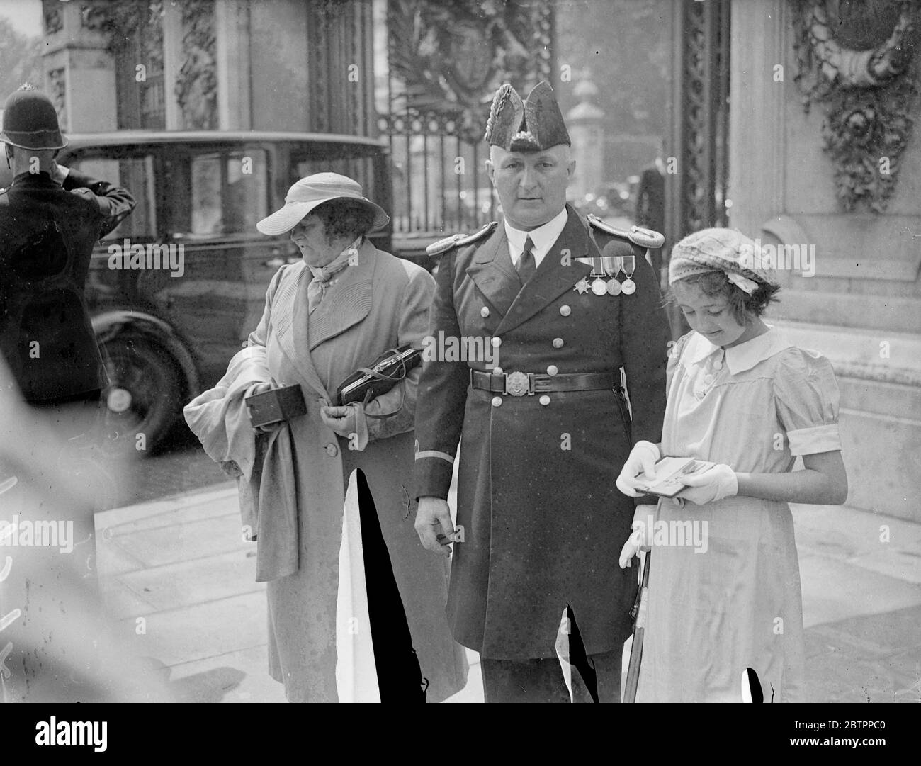 À l'investiture de Buckingham Palace. Une investiture a été organisée par le Roi au Palais de Buckingham, le premier à y avoir lieu pendant plusieurs années. La participation a été principalement constituée d'admissions et de promotions dans les classes supérieures des ordres de Chivalry, faites dans les honneurs d'anniversaire. Photos, commande de Botswain Foxworthy montrant son OBE à sa fille, Rosemary, comme il part après avoir assisté à l'investiture. 5 juillet 1938 Banque D'Images