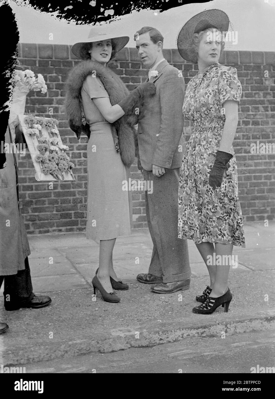 Boutonnière pour Lord. Mlle Betty Archer, l'une des célèbres jumeaux de la Société, épingle une nation dans le boutonnière de son frère quand ils sont arrivés au sol de Lord pour le deuxième jour du match Eton et Harrow. Sur la droite se trouve Lslie, l'autre jumeau. 9 juillet 1938. Banque D'Images