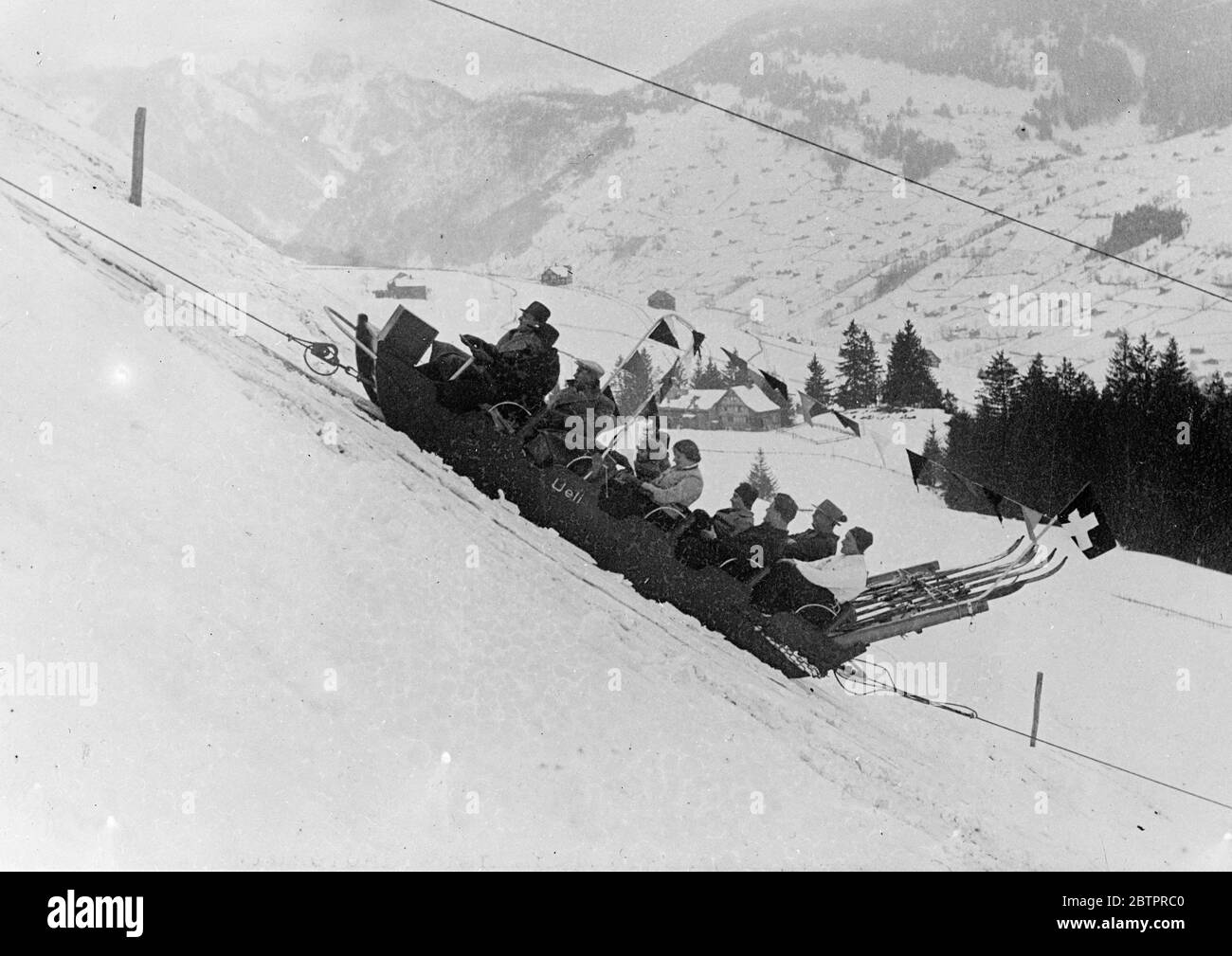 Economiseur de main-d'œuvre pour les skieurs. Une fête de ski sur les pistes enneigées d'une montagne à la station de sports d'hiver de la Suisse orientale par le traîneau des skieurs. Ce traîneau est tiré par un câble sans fin à environ un kilomètre sur le flanc de la montagne. Banque D'Images