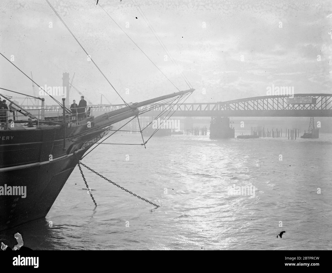 La découverte perce le coucher du soleil. Les arcs de la découverte se sont détourés contre le pont temporaire de Waterloo alors que le soleil couchant scintille la Tamise. La 'découverte', anciennement le navire d'exploration polaire, est maintenant la propriété des Scouts. 7 janvier 1938 Banque D'Images