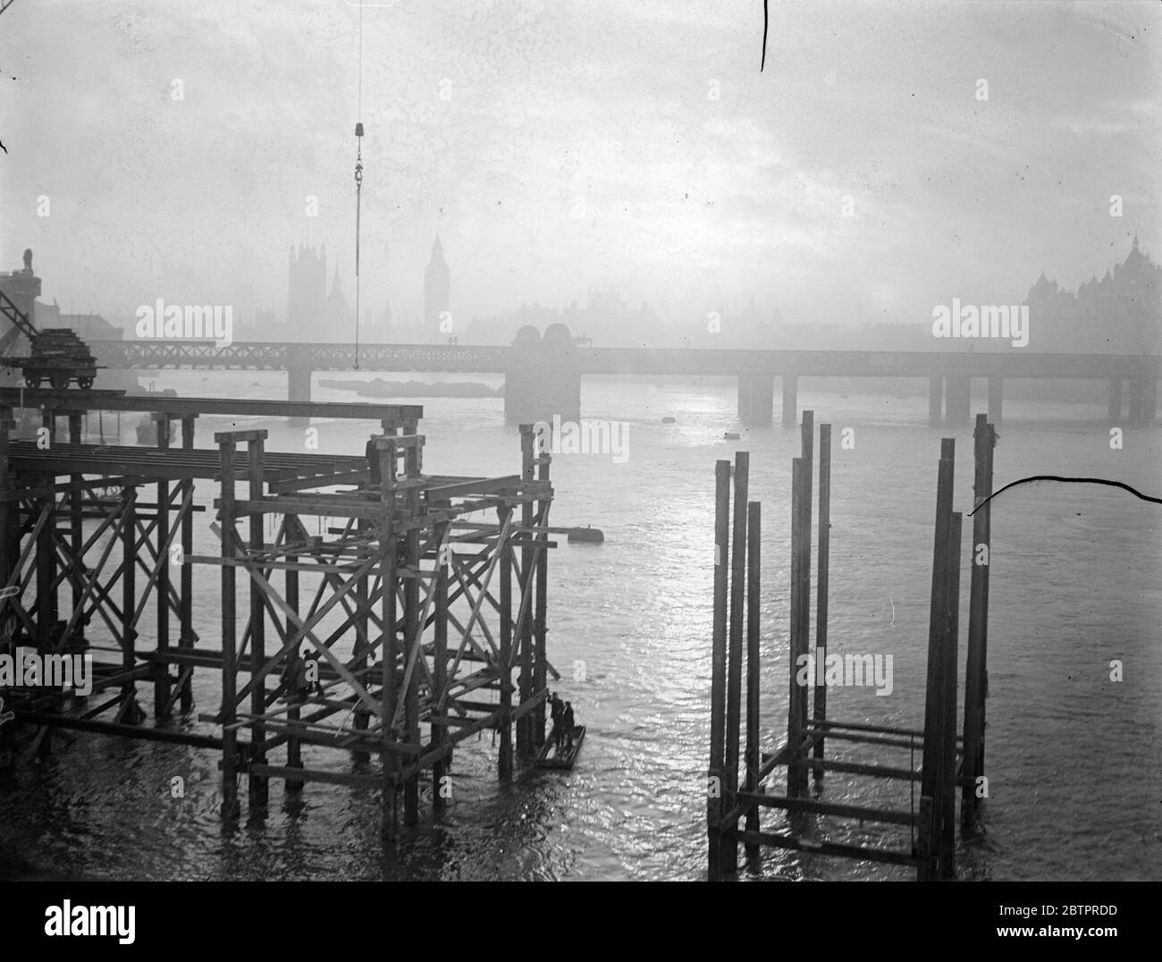Ombres du coucher de soleil de Londres. Le soleil couchant, qui brille à travers les nuages et qui envoie un chemin de lumière à travers la rivière sombre, jette dans l'ombre les piles du nouveau pont de Waterloo et, en arrière-plan, le pont Hungerford et les chambres du Parlement. 8 janvier 1938 Banque D'Images