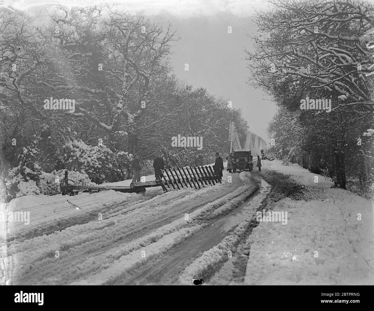 Blizzard shatters télégraphe pôles. Les bus, les voitures et les camions ont été maronés dans des galeries profondes, des câbles d'alimentation et des poteaux télégraphiques ont été ramenés et des arbres ont été balayés par la force du blizzard qui a balayé le sud de l'Angleterre. Des ravages pires ont été causés dans la région de la Nouvelle forêt, où les automobilistes ont été maroonés toute la nuit et plusieurs villes ont plongé dans l'obscurité. Photos, un mât de télégraphe cassé sur le chemin Lyndhurst à Bournemouth. 8 décembre 1937 Banque D'Images Blizzard shatters télégraphe pôles. Les bus, les voitures et les camions ont été maronés dans des galeries profondes, des câbles d'alimentation et des poteaux télégraphiques ont été ramenés et des arbres ont été balayés par la force du blizzard qui a balayé le sud de l'Angleterre. Des ravages pires ont été causés dans la région de la Nouvelle forêt, où les automobilistes ont été maroonés toute la nuit et plusieurs villes ont plongé dans l'obscurité. Photos, un mât de télégraphe cassé sur le chemin Lyndhurst à Bournemouth. 8 décembre 1937 Banque D'Images