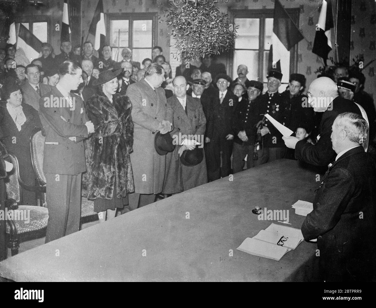 Josephine Baker épouse l'homme d'affaires français. Inconnue de ses amis, Josephine Baker, la célèbre danseuse, s'est mariée tranquillement à crevecoeur le Grand dans le département de l'Oise à M Jean Lion, un jeune homme d'affaires et aviateur français. Le maire de Crevecoeur a donné la cérémonie et M. Derval, directeur des Folies Bergère, en a été témoin. Mlle Baker vient à Londres dans quelques jours. Photos, le maire de Crevecoeur qui a effectué la cérémonie. Josephine Baker et son marié sont sur la gauche (souriant) sur la table pend un énorme tas de GUI, 30 novembre 1937 Banque D'Images