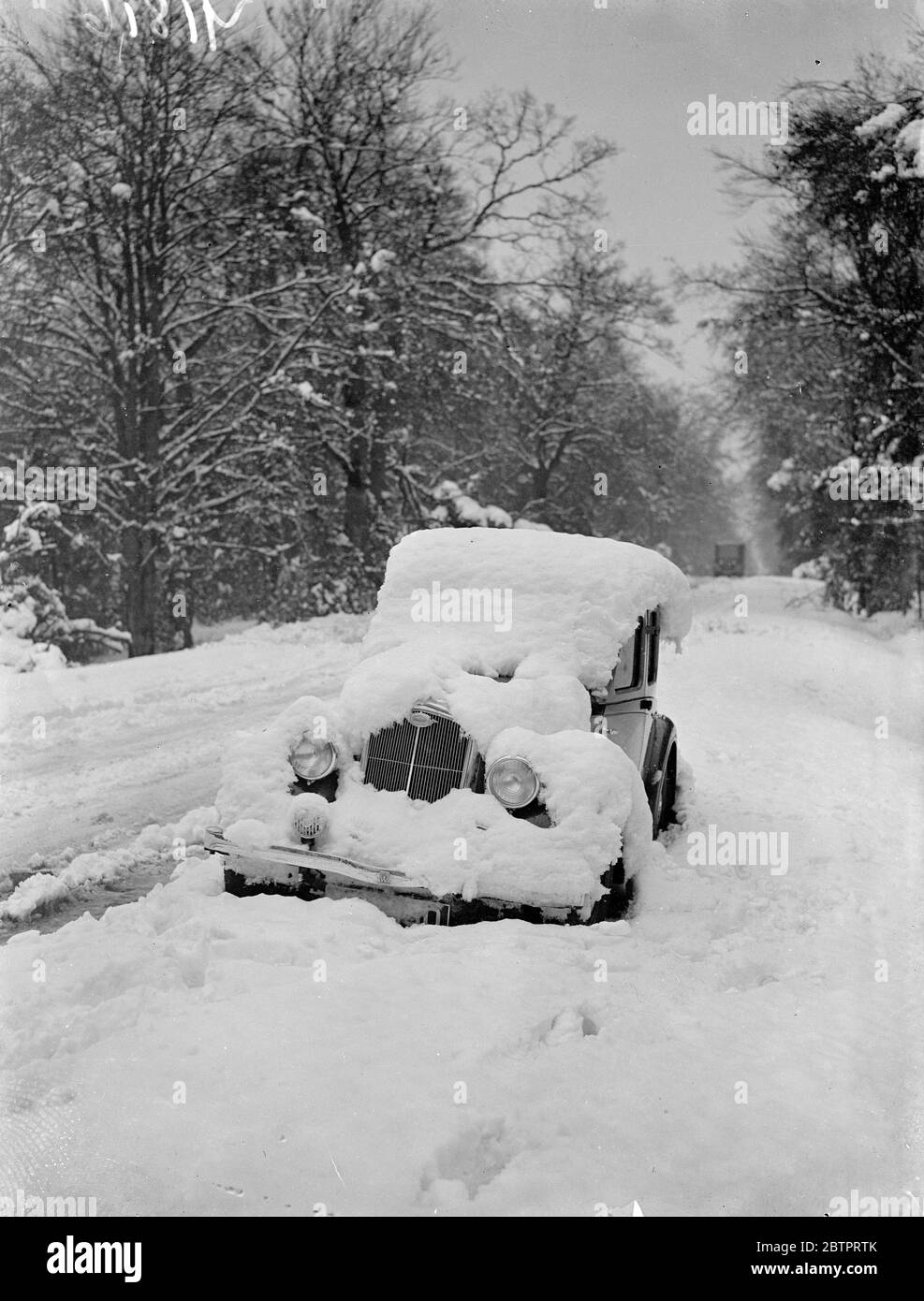 Neige « abandonnée » dans le Hampshire. Les pires tempêtes de neige de décembre depuis de nombreuses années ont semé le chaos sur la route du sud de l'Angleterre, où les voitures ont été laissées à la merci de la neige sur de nombreuses routes importantes, alors que les conducteurs cherchent un abri. Des expositions de photos et des charrettes abandonnées recouvertes de neige épaisse sur la route de Cadnum - Ringwood dans le Hampshire. 9 décembre 1937 Banque D'Images
