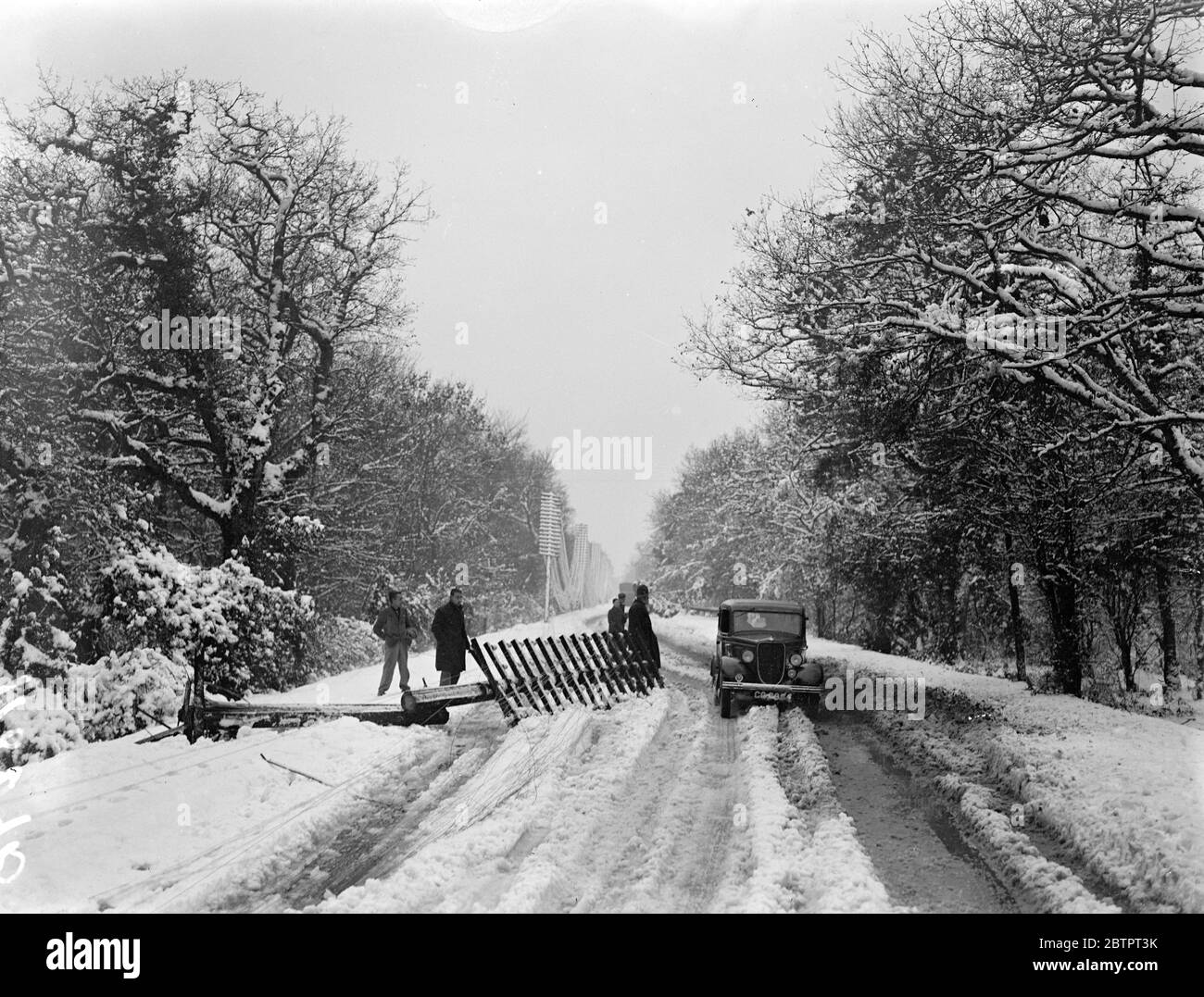 Blizzard shatters télégraphe pôles. Les bus, les voitures et les camions ont été maronés dans des galeries profondes, des câbles d'alimentation et des poteaux télégraphiques ont été ramenés et des arbres ont été balayés par la force du blizzard qui a balayé le sud de l'Angleterre. Des ravages pires ont été causés dans la région de la Nouvelle forêt, où les automobilistes ont été maroonés toute la nuit et plusieurs villes ont plongé dans l'obscurité. Photos, un mât de télégraphe cassé sur le chemin Lyndhurst à Bournemouth. 8 décembre 1937 Banque D'Images Blizzard shatters télégraphe pôles. Les bus, les voitures et les camions ont été maronés dans des galeries profondes, des câbles d'alimentation et des poteaux télégraphiques ont été ramenés et des arbres ont été balayés par la force du blizzard qui a balayé le sud de l'Angleterre. Des ravages pires ont été causés dans la région de la Nouvelle forêt, où les automobilistes ont été maroonés toute la nuit et plusieurs villes ont plongé dans l'obscurité. Photos, un mât de télégraphe cassé sur le chemin Lyndhurst à Bournemouth. 8 décembre 1937 Banque D'Images