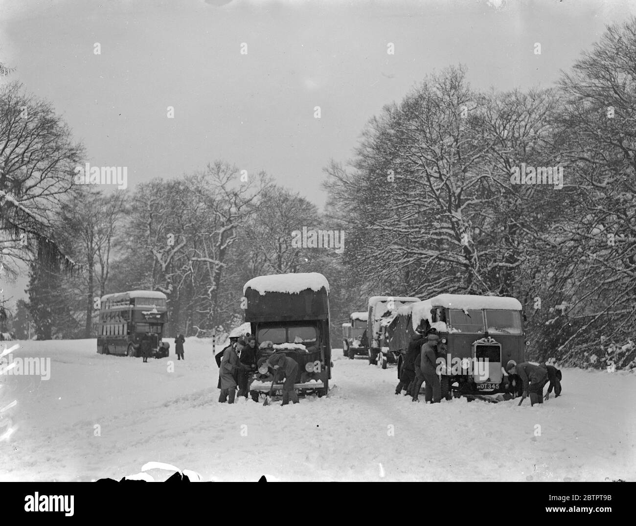 Déneigement dans le sud de l'Angleterre. Trafic bloqué. Le plus grand chaos de la grande tempête de neige qui a ravagé le sud de l'Angleterre a été causé dans le district de Lyndhurst dans la Nouvelle forêt, où les fils téléphoniques ont été déchirés au fur et à mesure que les arbres sont tombés, coupant les communications dans toutes les directions. Les routes principales ont été bloquées et le district a plongé dans l'obscurité par la rupture des câbles d'alimentation. Expositions de photos, circulation enneigée sur la route Lyndhurst. 8 décembre 1937 Banque D'Images