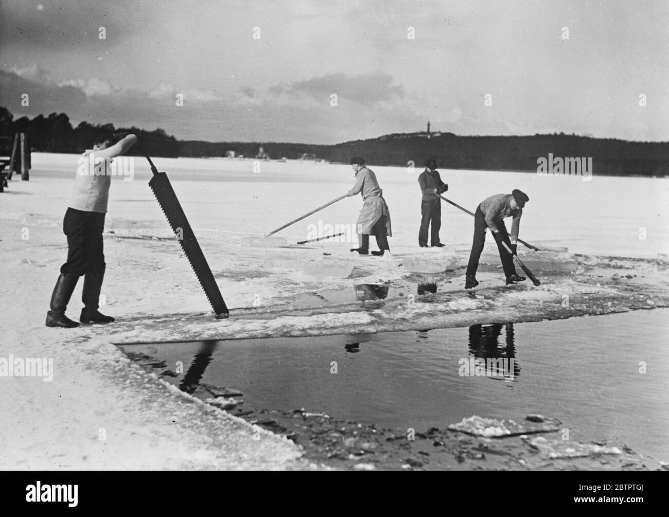Couper la récolte de glace . Pour la première fois en plusieurs années, les lacs et étangs de Berlin ont gelé assez dur pour récolter la glace . Les employés des sociétés de glace de Berlin coupent la glace pour le stockage à Berlin . 15 février 1932 Banque D'Images