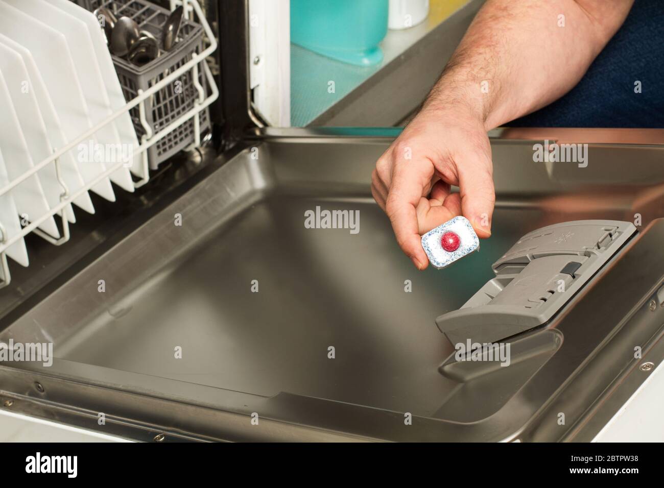 Homme mettant une tablette de détergent dans le lave-vaisselle Banque D'Images