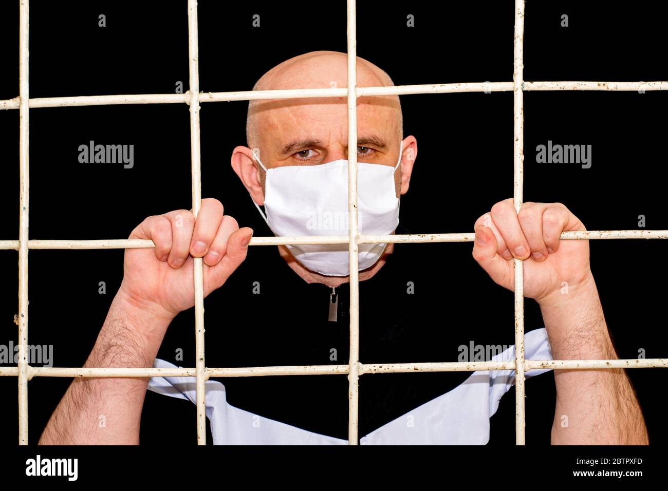 Confinement et quarantaine d'une pandémie concept UN homme bald d'âge moyen dans un masque d'hygiène médical tenant des barres de fer avec ses mains Banque D'Images