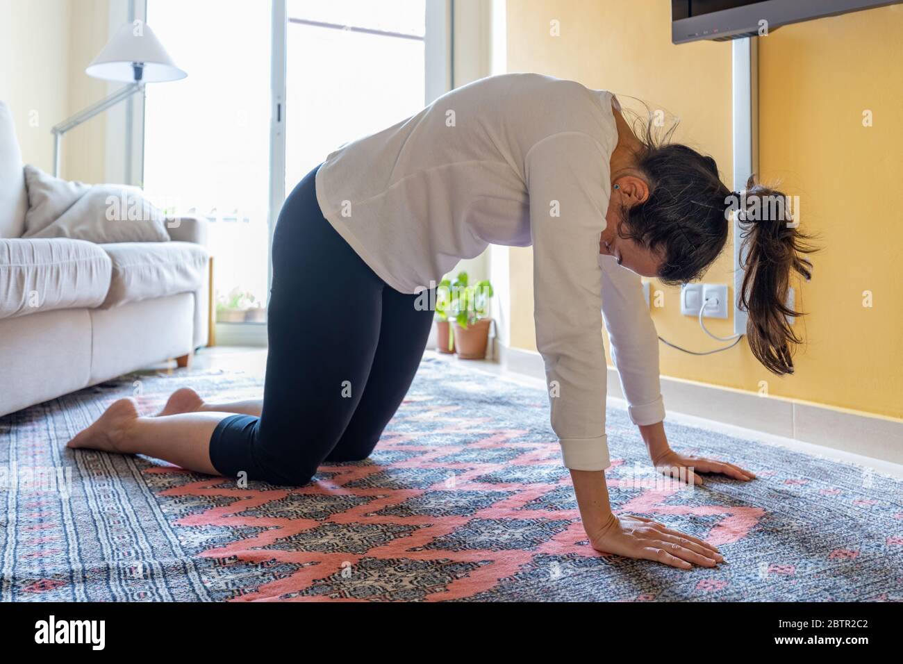 Jolie fille espagnole faisant de la gymnastique à la maison dans le salon Banque D'Images