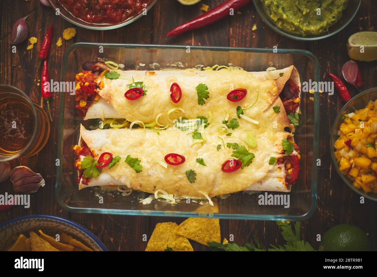 Burritos de légumes servis dans un plat en verre résistant à la chaleur. Avec salsa, guacamole, nachos et ingrédients Banque D'Images