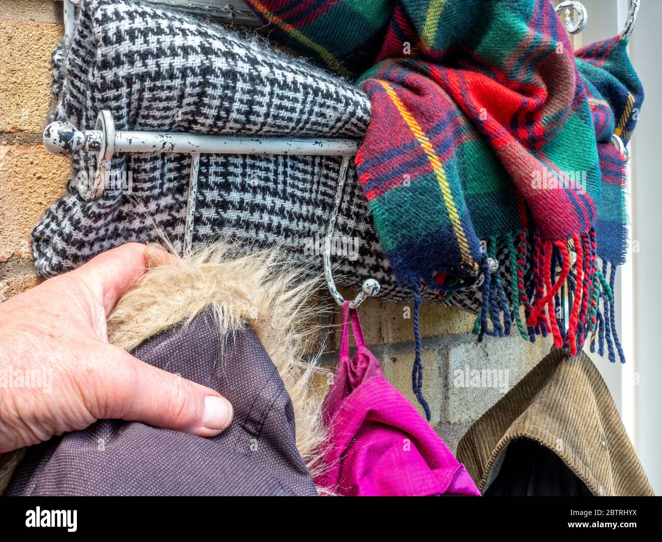 Gros plan POV prise de vue d'un homme portant un manteau d'hiver sur un  crochet, avec des foulards de laine colorés pressés dans le rack ci-dessus  Photo Stock - Alamy
